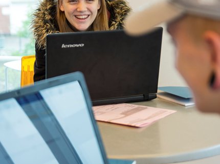 girl smiling over the top of a laptop