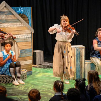 Ruby sits on an old tire, surrounded by three musicians