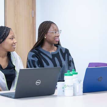 Tutor sitting speaking to two learners