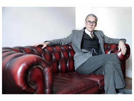 Andrew Graves sitting on a Chesterfield sofa wearing a three-piece suit