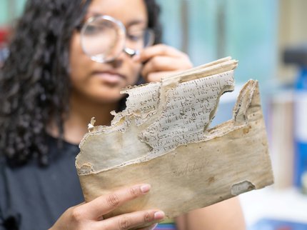 A person looking at an old document through a magnifying glass