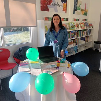 Person stood behind a stall decorated with pastel balloons