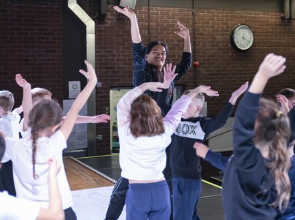 A group of people dancing in a studio with paper on the ground