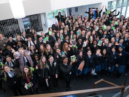 A big group of students smiling and holding books