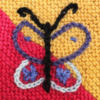 Image of embroidered chain stitch butterfly motif in bright coloured wool yarns