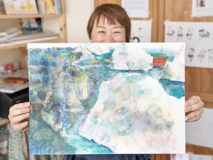 Photo of artist holding up a pastel drawing.