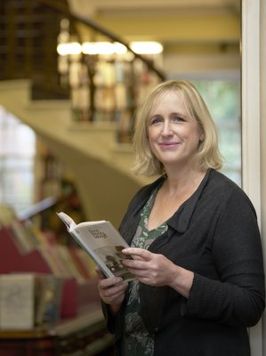 Clare Brown smiling, with a book