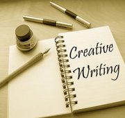 notebook open with quill and ink and text that reads creative writing