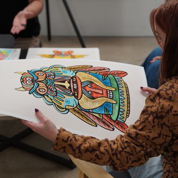 Back of a woman's head holding a colourful piece of art