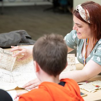 A woman showing a young boy artefacts and documents on a table