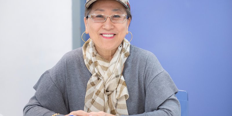 A smiling woman wearing a cap and glasses
