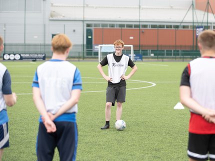 A young person coaching a football group.