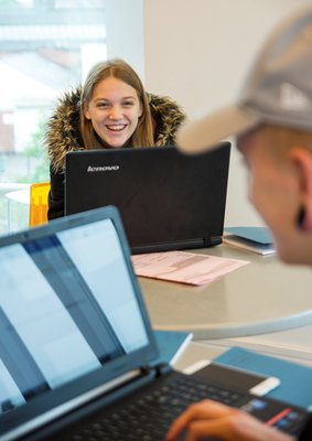 girl smiling over the top of a laptop