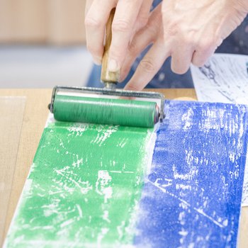 Photograph of artist rolling green printing ink onto a foam sheet