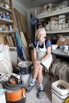 woman sat with apron on in pottery studio