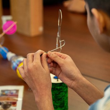 A closeup of a child’s hands making a scientific model.