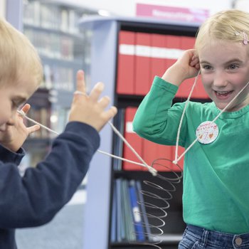 A boy and a girl do a science experiment with a spring and some string.