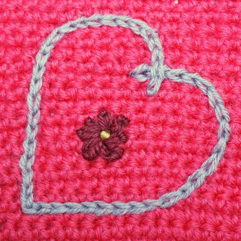 Image of embroidered chain stitch heart and flower in bright coloured wool yarns
