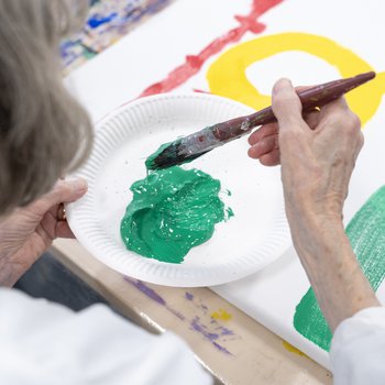 Lady from Blidworth Memory Group painting with green paint on a abstract canvas