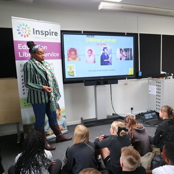 A group of children sit on a floor at an author workshop