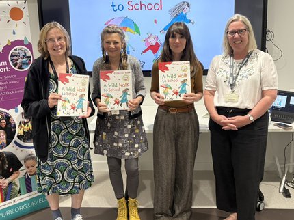 A photo of four women standing in a row holding books