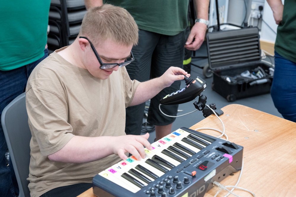 Man with glasses sitting down playing a keyboard