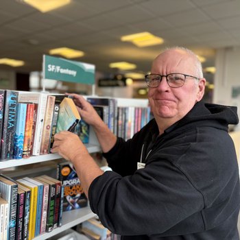 Member of staff shelving a book smiling