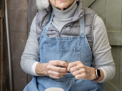 Photo of woman sat behind a potters wheel with a upturned pot on the wheel head.