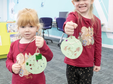 Two children smiling with bauble crafts