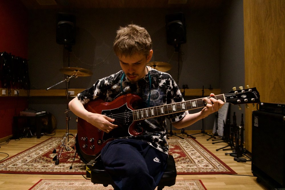 Man sitting down playing a guitar