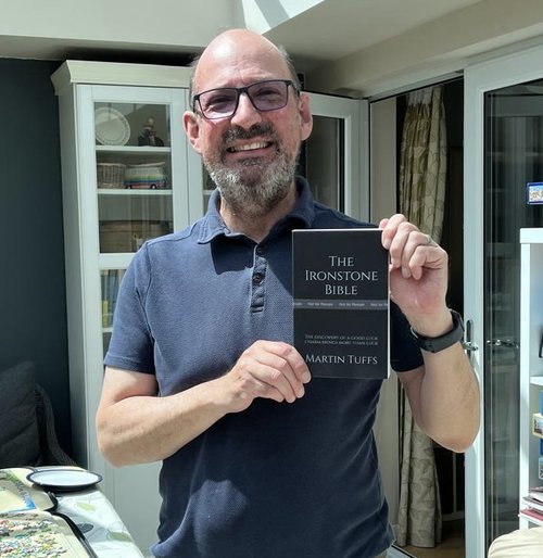 A man in a blue tshirt holding a book