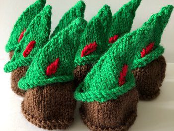 Knitted green robin hood hats with a red knitted feather