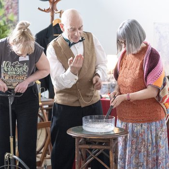 A group of people standing around a water bowl, one dressed in victorian clothing