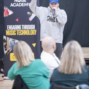 A man in a grey hoodie and blue cap raps