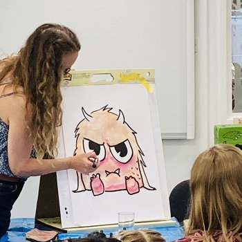 Photograph of artist Amanda Rigby doing a drawing demonstration of a monster