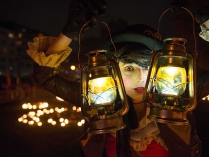 A child in costume holding two lanterns in front of them