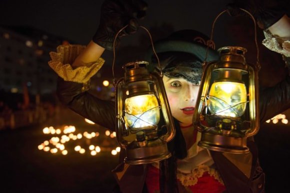 A child in costume holding two lanterns in front of them