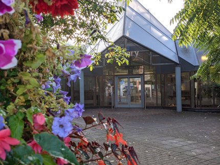 An exterior photo of Newark Library's entrance, with bright flowers in the foreground.