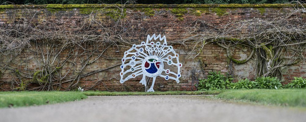 Photo of peacock sculpture in formal garden