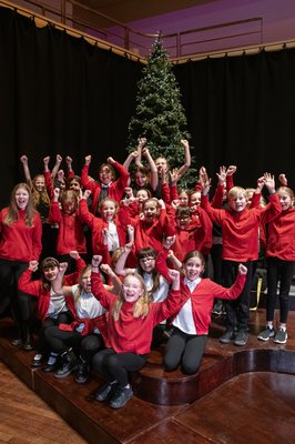 A group of primary school children with a christmas tree on stage