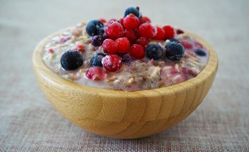 A wooden bowl full of overnight oats and Summer Berries