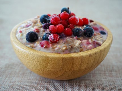 A wooden bowl full of overnight oats and Summer Berries