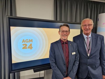 Peter Gaw and John Cottee pictured in front of screen with AGM 24 graphic