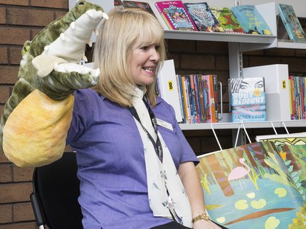 member of staff reading picture book using a puppet of a crocodile