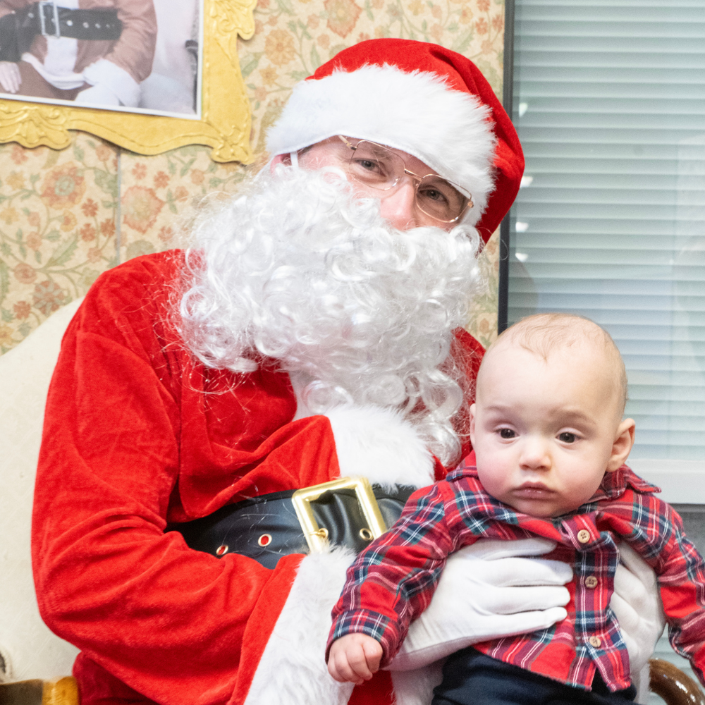 Santa in his grotto with a baby on his knee