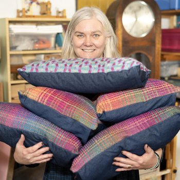 Photo of woman holding a pile of hand woven cushions