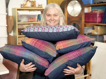 Photo of woman holding a pile of hand woven cushions