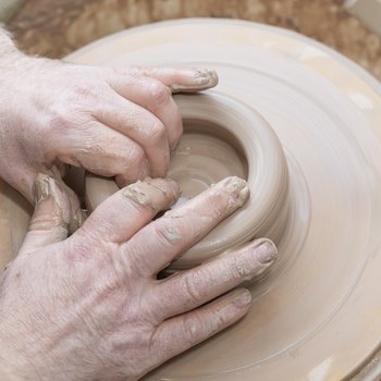 Photo of man throwing a clay pot on a wheel.