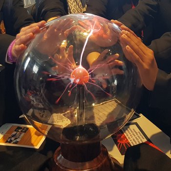 Four pairs of children's hands placed on a plasma ball