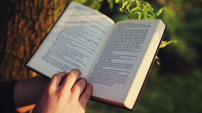 Hands holding a book, outside in nature